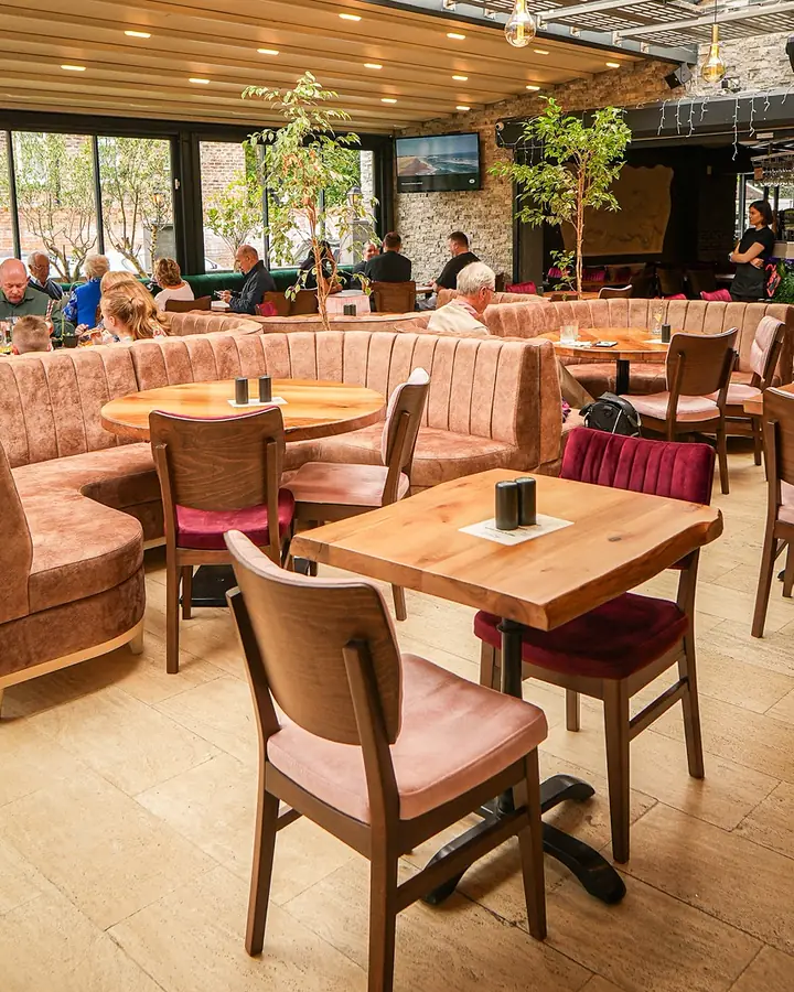 Pink velvet booths and wooden tables inside Al Dente