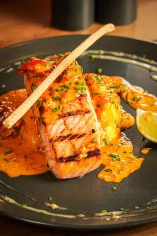 Grilled salmon fillet in a bright orange sauce